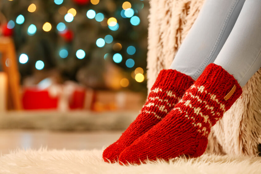Woman in warm socks at home on Christmas eve, closeup